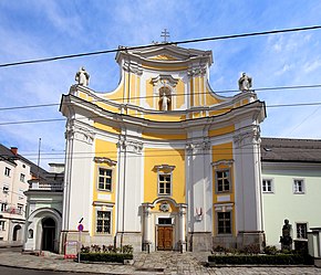 Hauptfassade der Klosterkirche mit einer Steinstatue des Ordensgründer hl. Johannes von Gott in der Rundbogennische